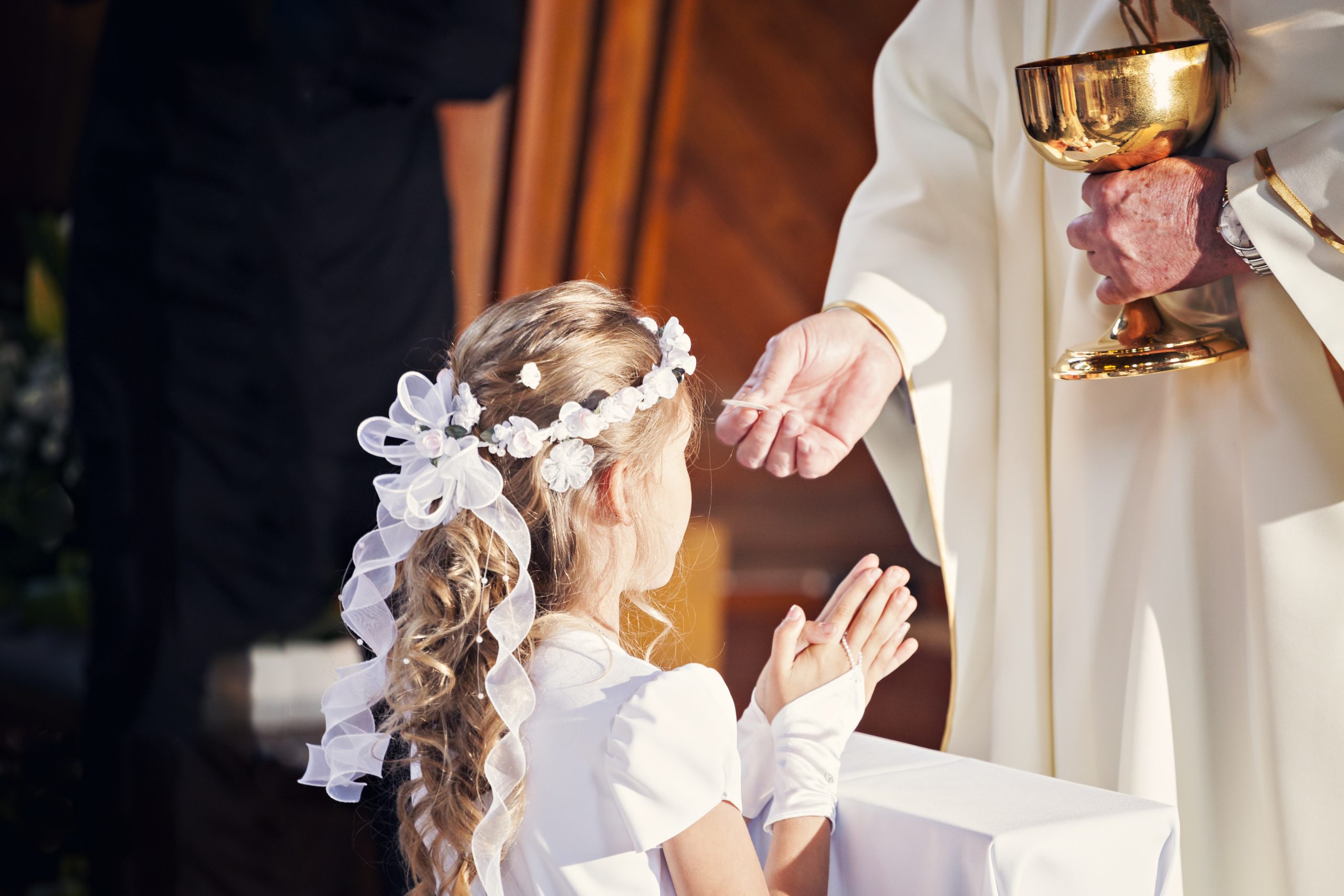 Communion and clergyman. Priest holds Holy Communion in his hands. Priest gives the Body of Christ during the First Holy Communion